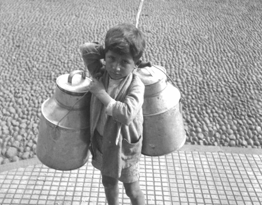 Boy with two milk canisters on his shoulders