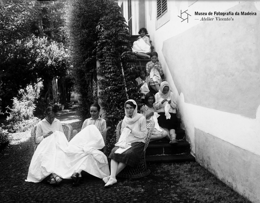 Grupo de mulheres e crianças a bordar